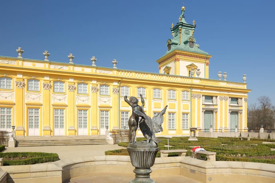 Un bâtiment jaune avec une tour verte et une statue représentant une figure ailée.