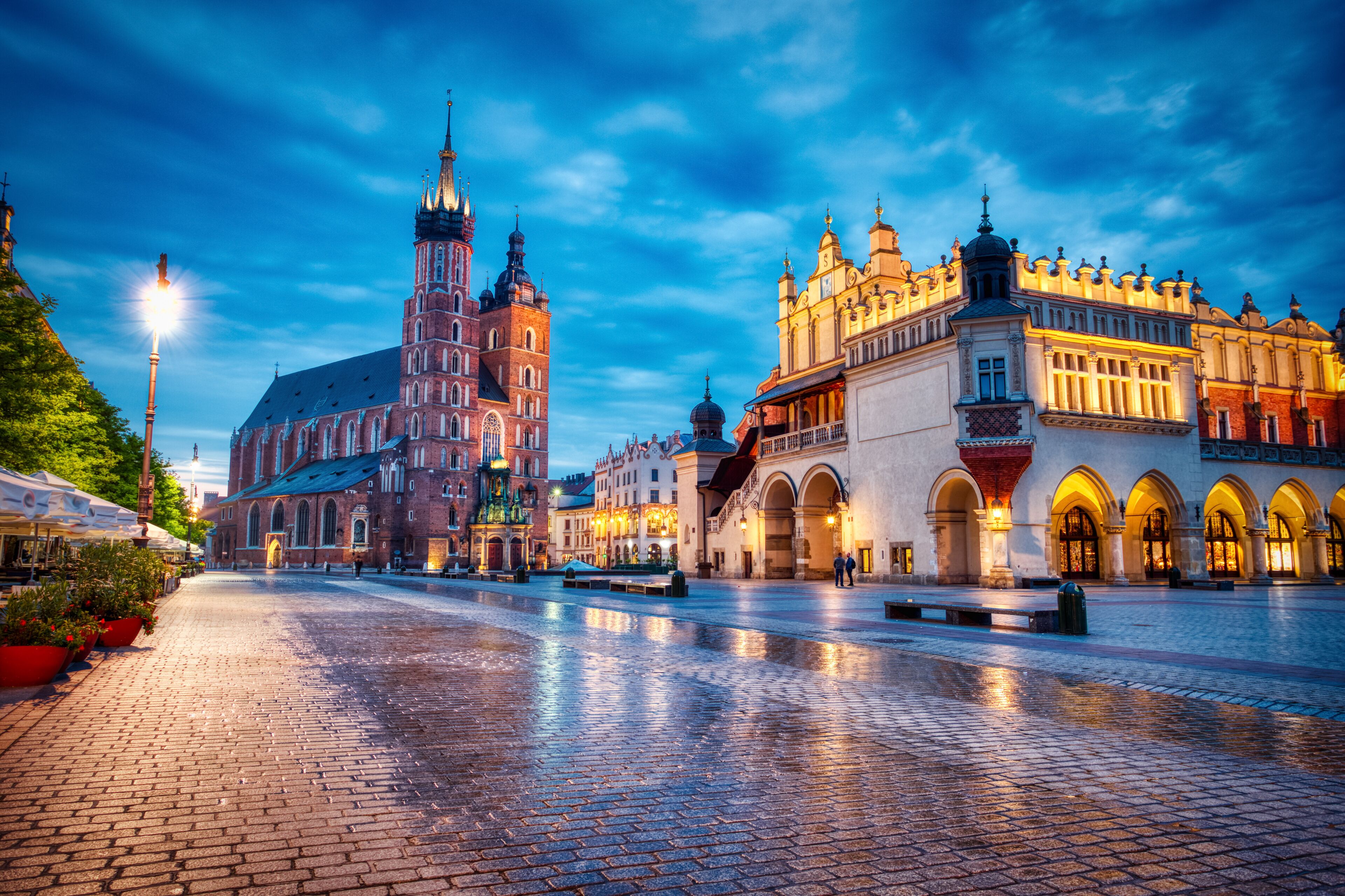 A historic square with a prominent church, a market building, and a well-lit street.