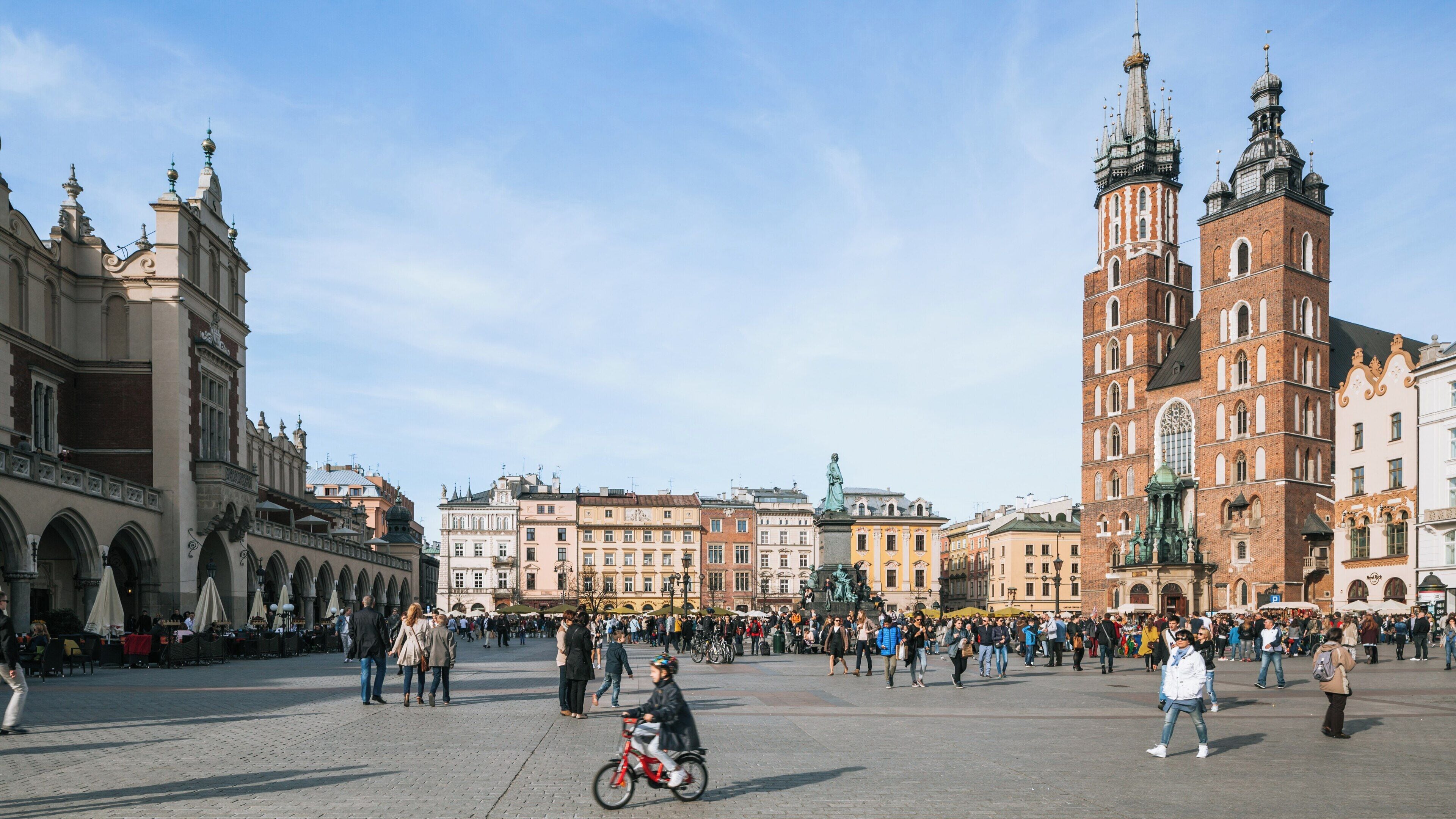 Stunning view of St. Mary's Basilica in Kraków City Centre with bustling market square during a sunny day