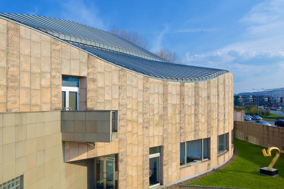 A modern building with a curved facade and a sloped roof.