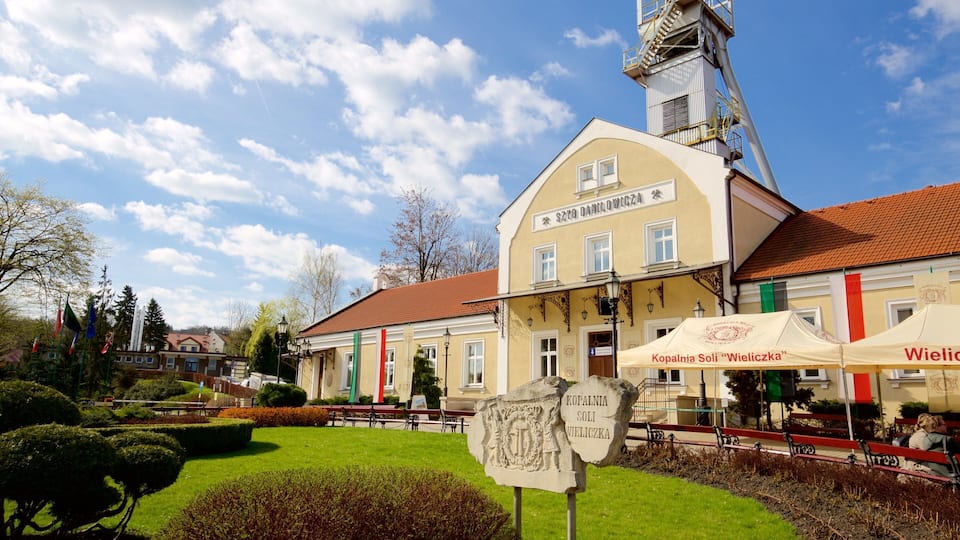 A historic building with a clock tower, surrounded by well-maintained gardens and a clear blue sky.