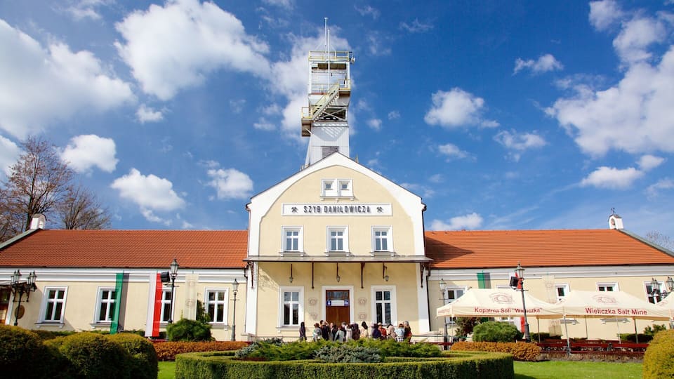 A building with a red roof and a tower. There are people gathered in front of the building.
