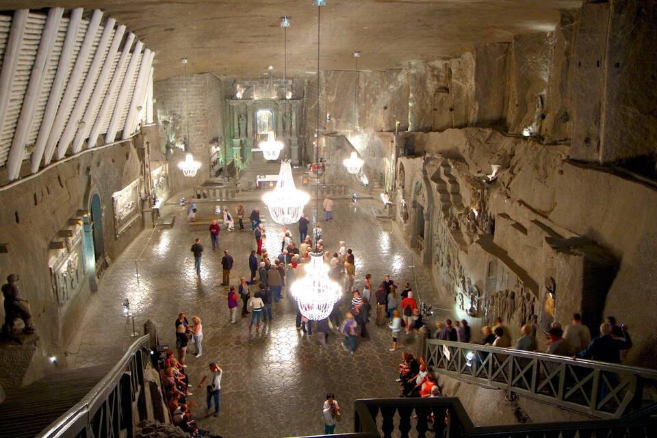 An underground cathedral with a crowd of visitors, stone walls, and chandeliers.