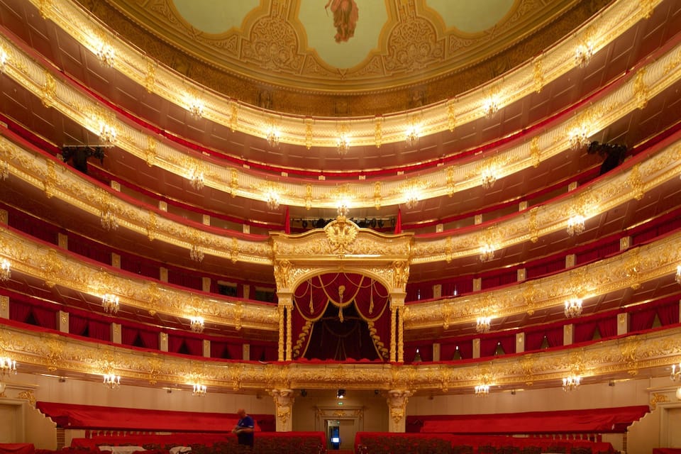 A grand, ornate theater with multiple balconies and red curtains.