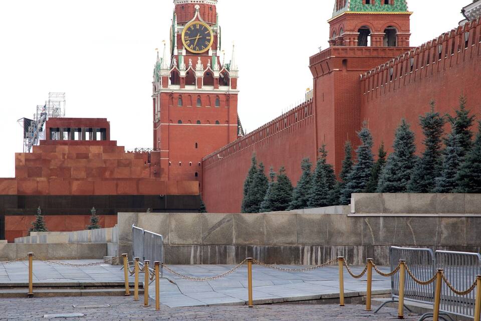 A historic red brick wall with a clock tower and a sign in Russian.