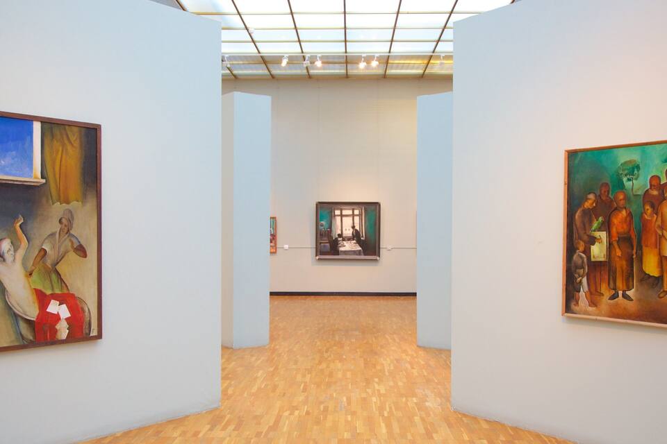 An art gallery with wooden floors and paintings on the walls.