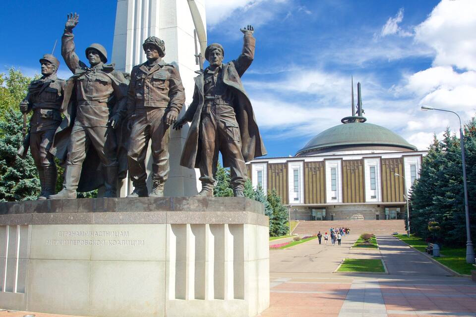A statue of soldiers with raised arms in front of a building with a dome.