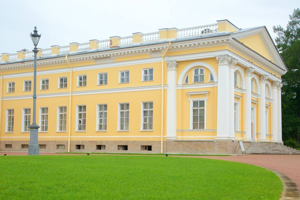Un edifici gran de color groc amb adorns blancs, un fanal i un camp de gespa verd.