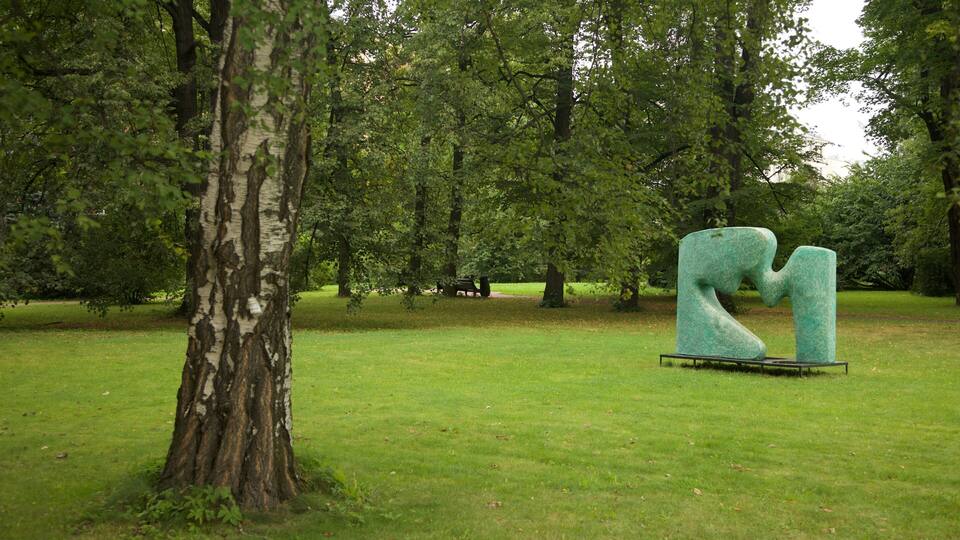 A sculpture in a park with a large tree and a grassy area.