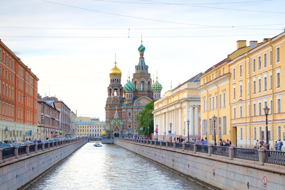 A canal with a historic building with colorful domes in the background.