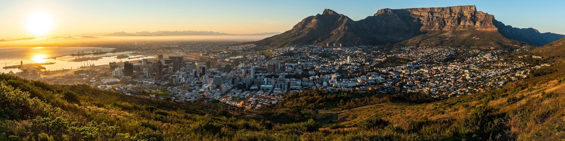 A cityscape with a prominent mountain range in the background.