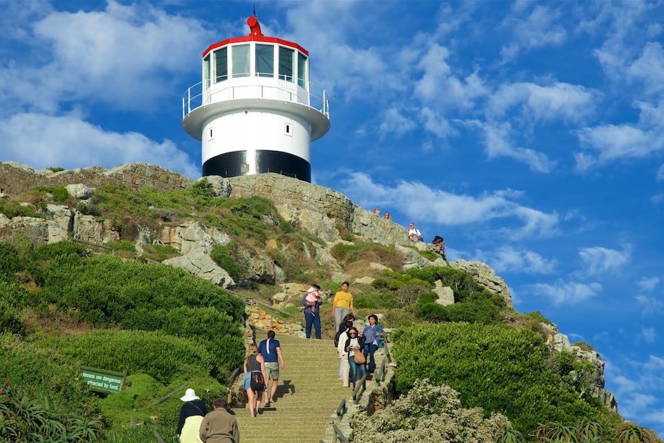 Un phare perché sur une colline rocheuse, avec des personnes qui montent les escaliers.