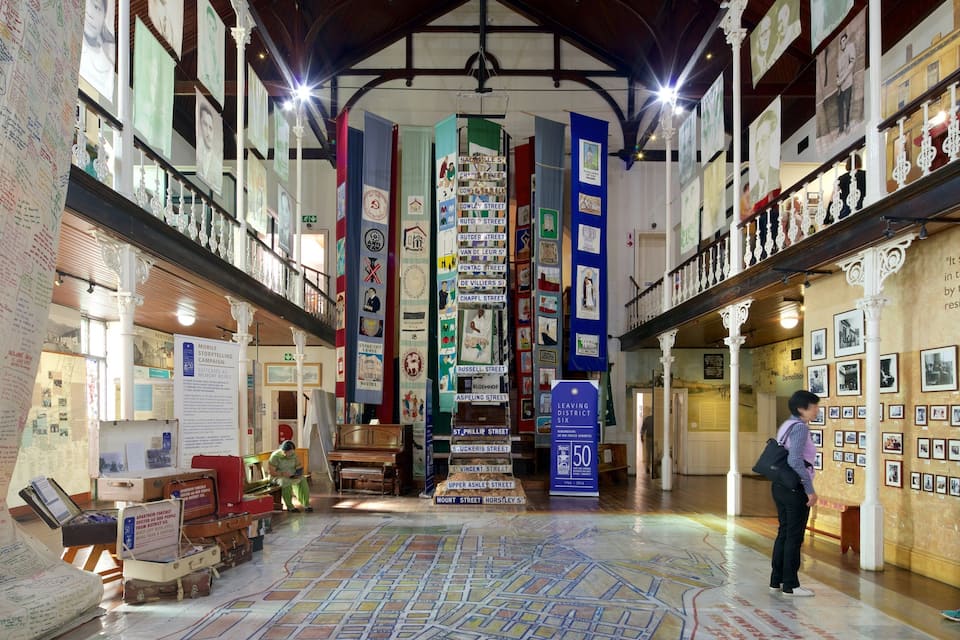 Interior de museu com um mapa, placas de rua históricas e fotografias nas paredes.