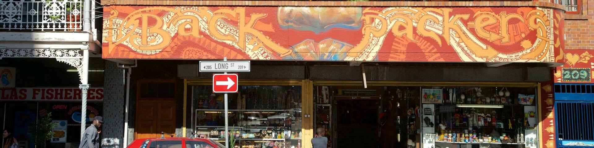 A colorful building with intricate murals, a red car parked in front, and a sign for 'Las Ficheres'.