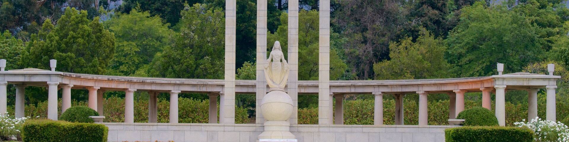 A monument with a star on top, surrounded by greenery and mountains.