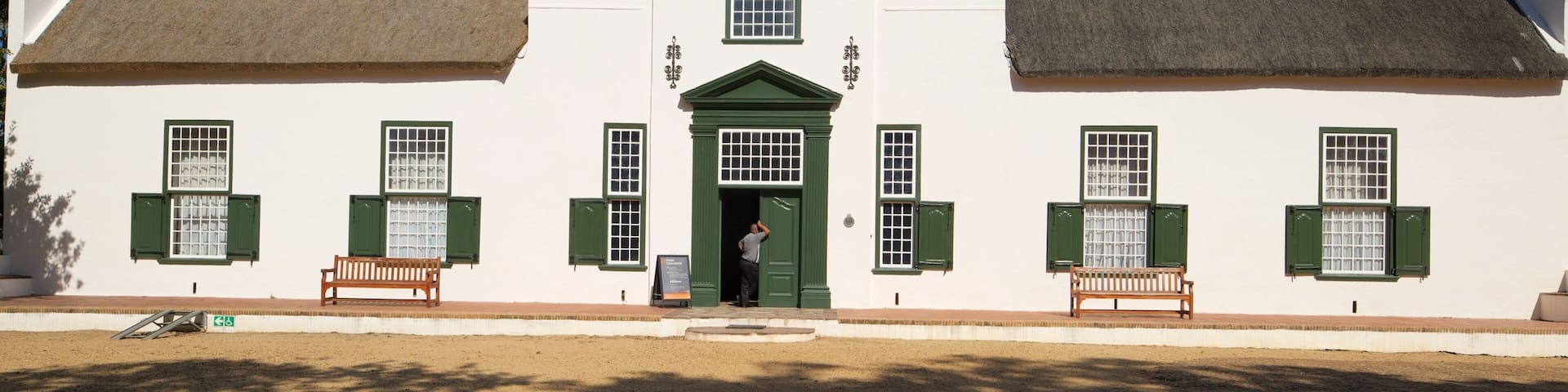 A colonial-style building with a white facade, green shutters, and a central entrance.