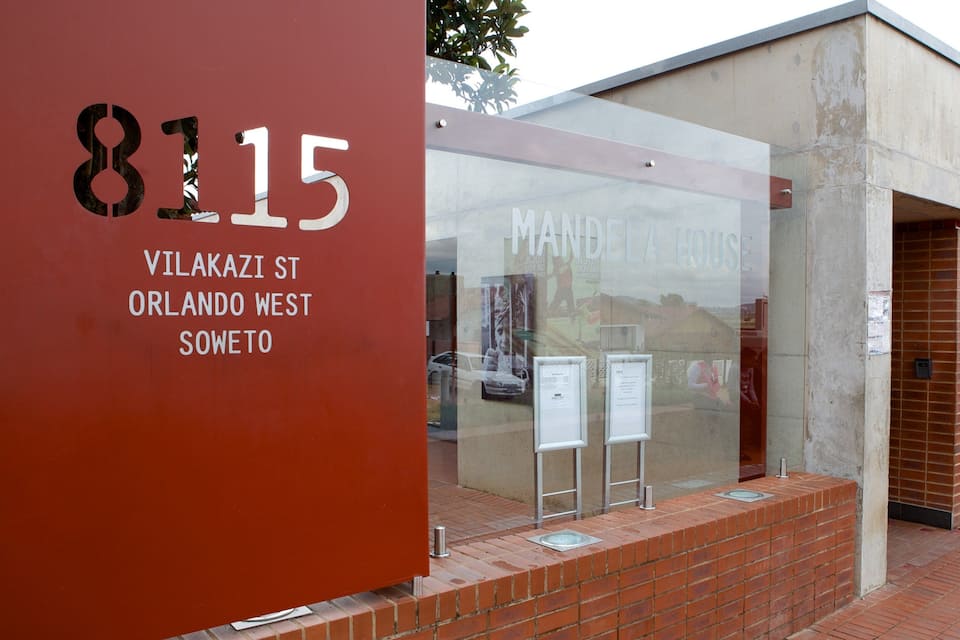 Un edifici amb un rètol que diu “8315 Vilakazi St, Orlando West, Soweto” i una porta de vidre amb la frase “Mandela House” visible.