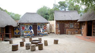 A traditional village with thatched-roof huts, colorful murals, and wooden stools.