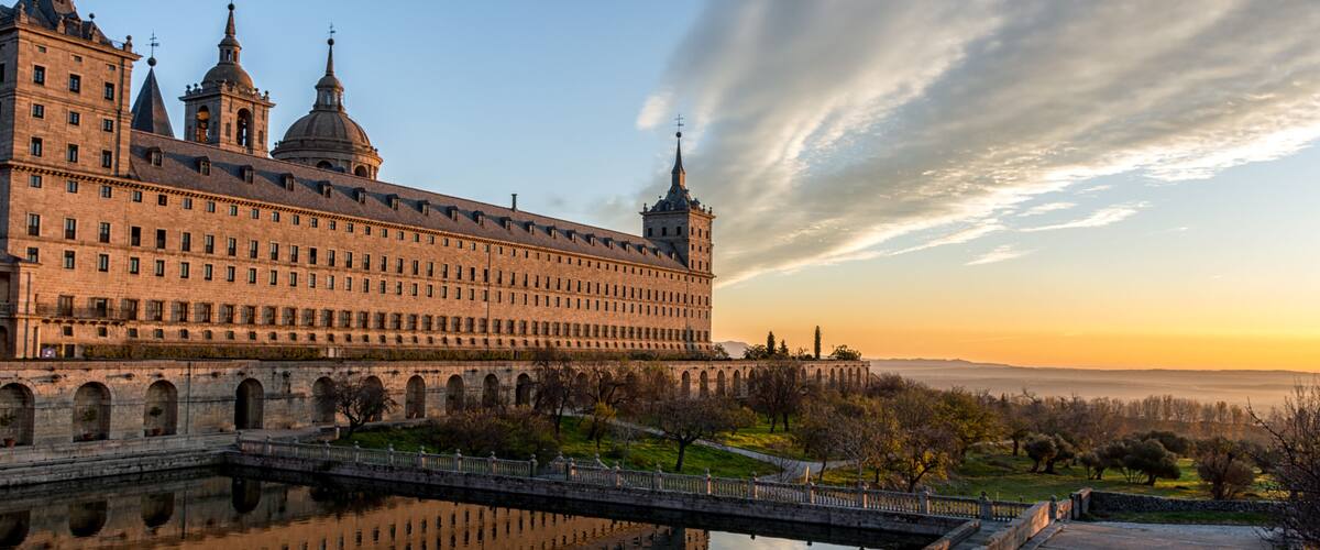 A historic building with multiple towers and a reflection in the water.