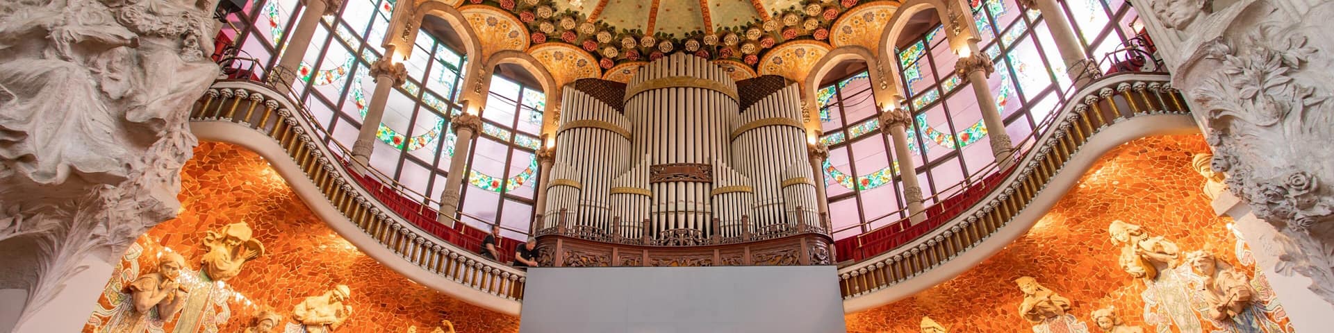 A grand hall with ornate mosaics, a large organ, and a high ceiling with intricate designs.