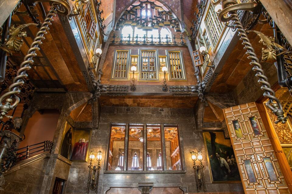 Un intérieur somptueux, avec un plafond haut, des éléments de ferronnerie complexes et des vitraux.