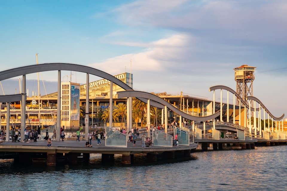 Un paseo marítimo con un puente moderno, un restaurante y una torre.