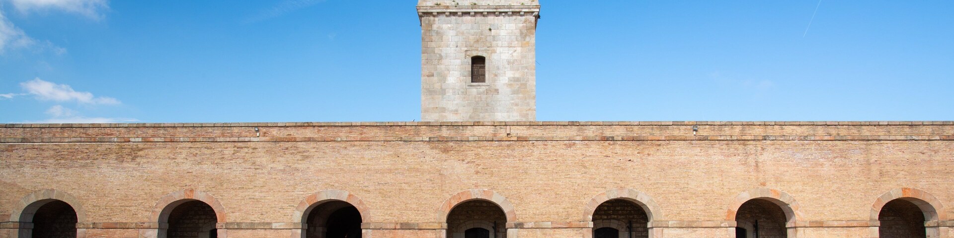 Montjuic Castle showing heritage architecture and a square or plaza as well as an individual femail