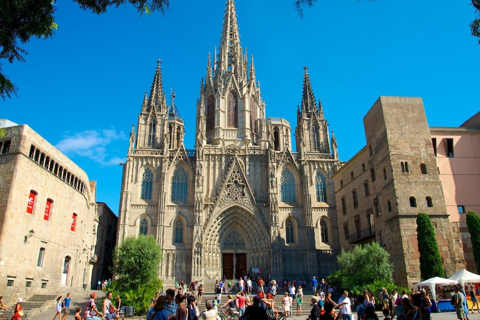 Une cathédrale historique à l’architecture gothique complexe, entourée de touristes et de bâtiments modernes.