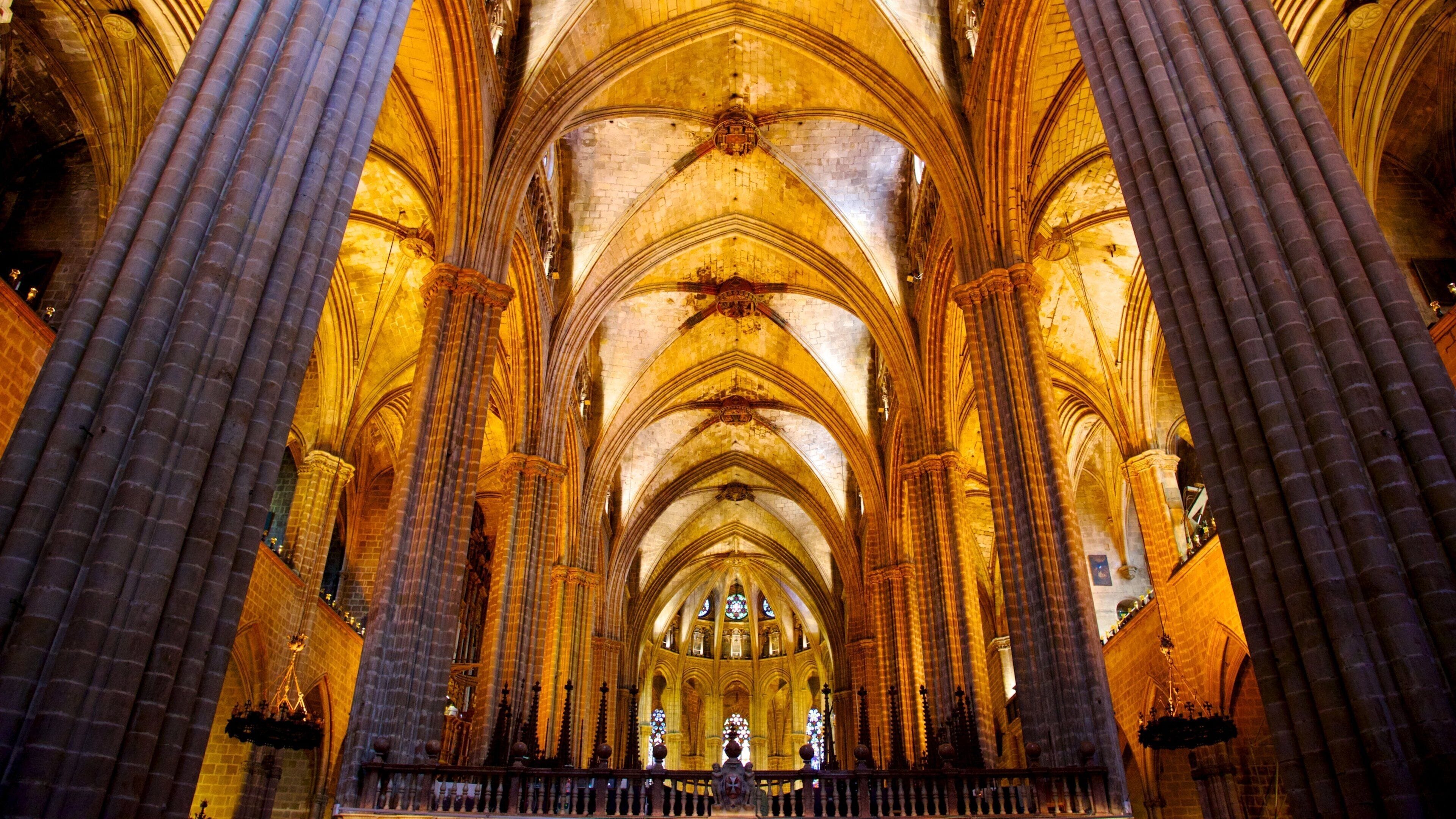Interior de uma catedral com altos tetos abobadados, grandes colunas e vitrais.