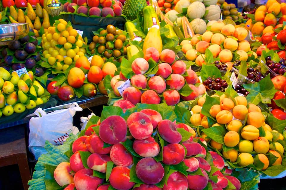 Diversas frutas, como pêssegos, maçãs e peras, em um mercado.