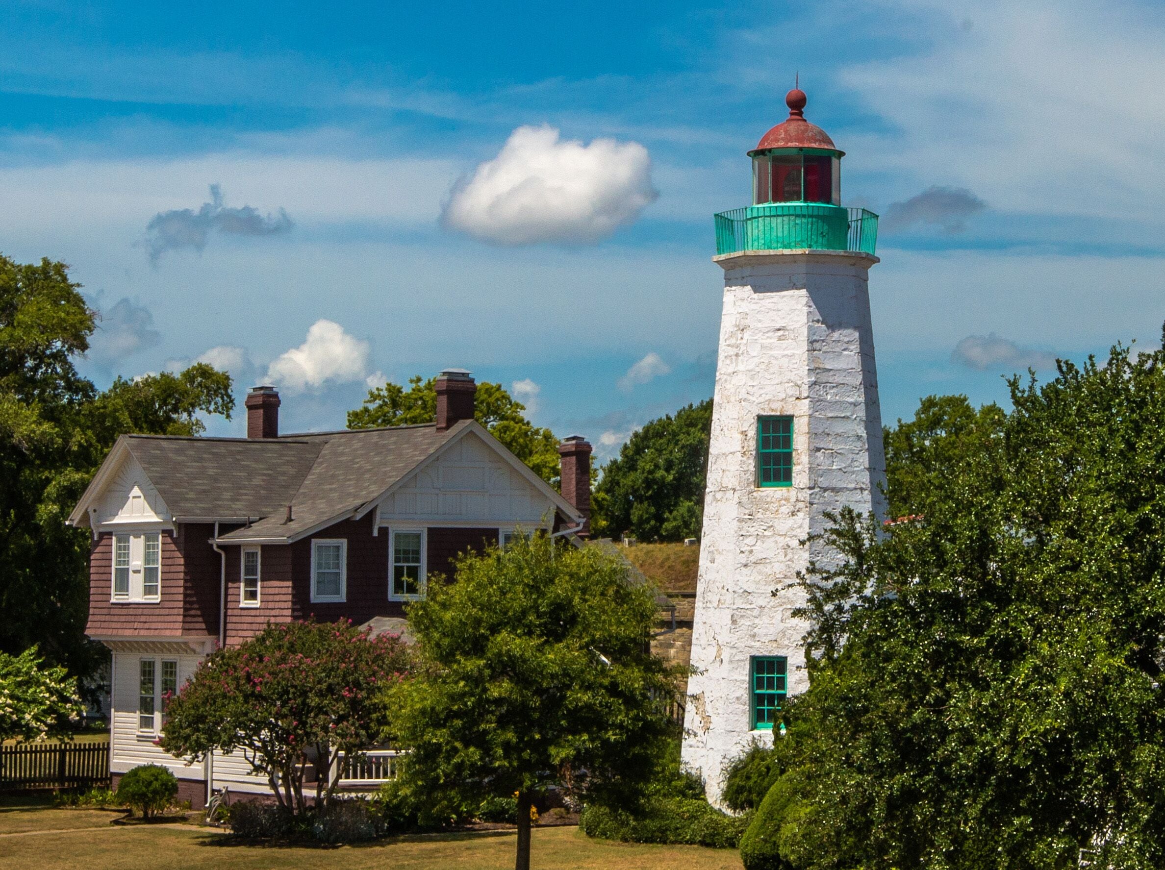 A lighthouse and a house with a red roof.