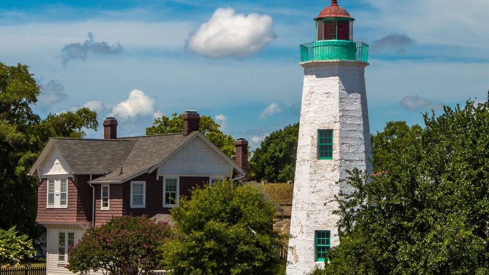 A lighthouse and a house with a red roof.