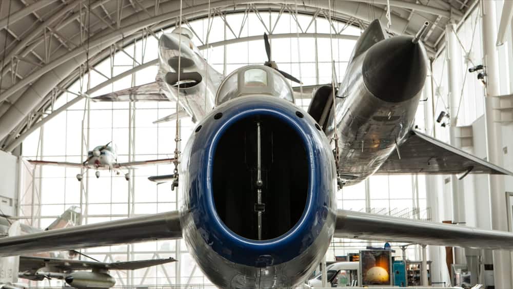 An aircraft with a blue nose cone and silver wings inside a hangar.