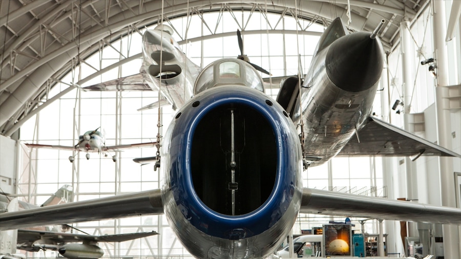 Un avión con cono de morro azul y alas plateadas dentro de un hangar.