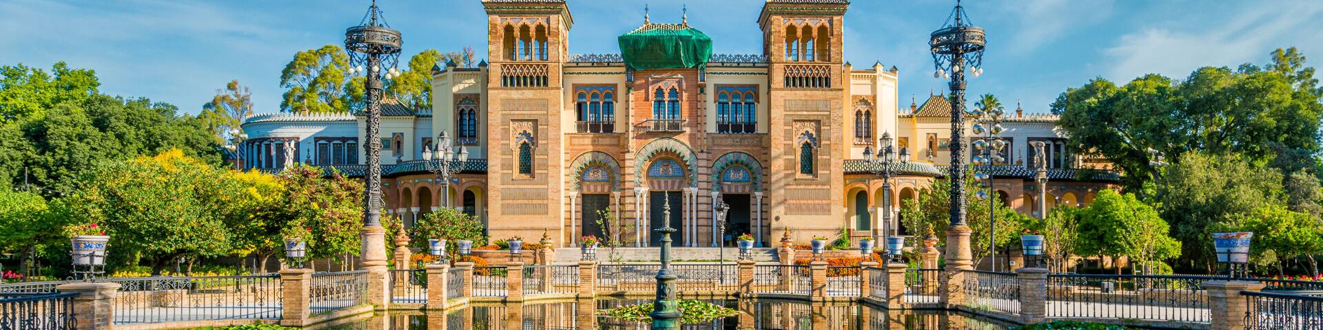 Museum of Popular Arts and Traditions reflecting in the near fountain in Seville, Andalusia, Spain.
