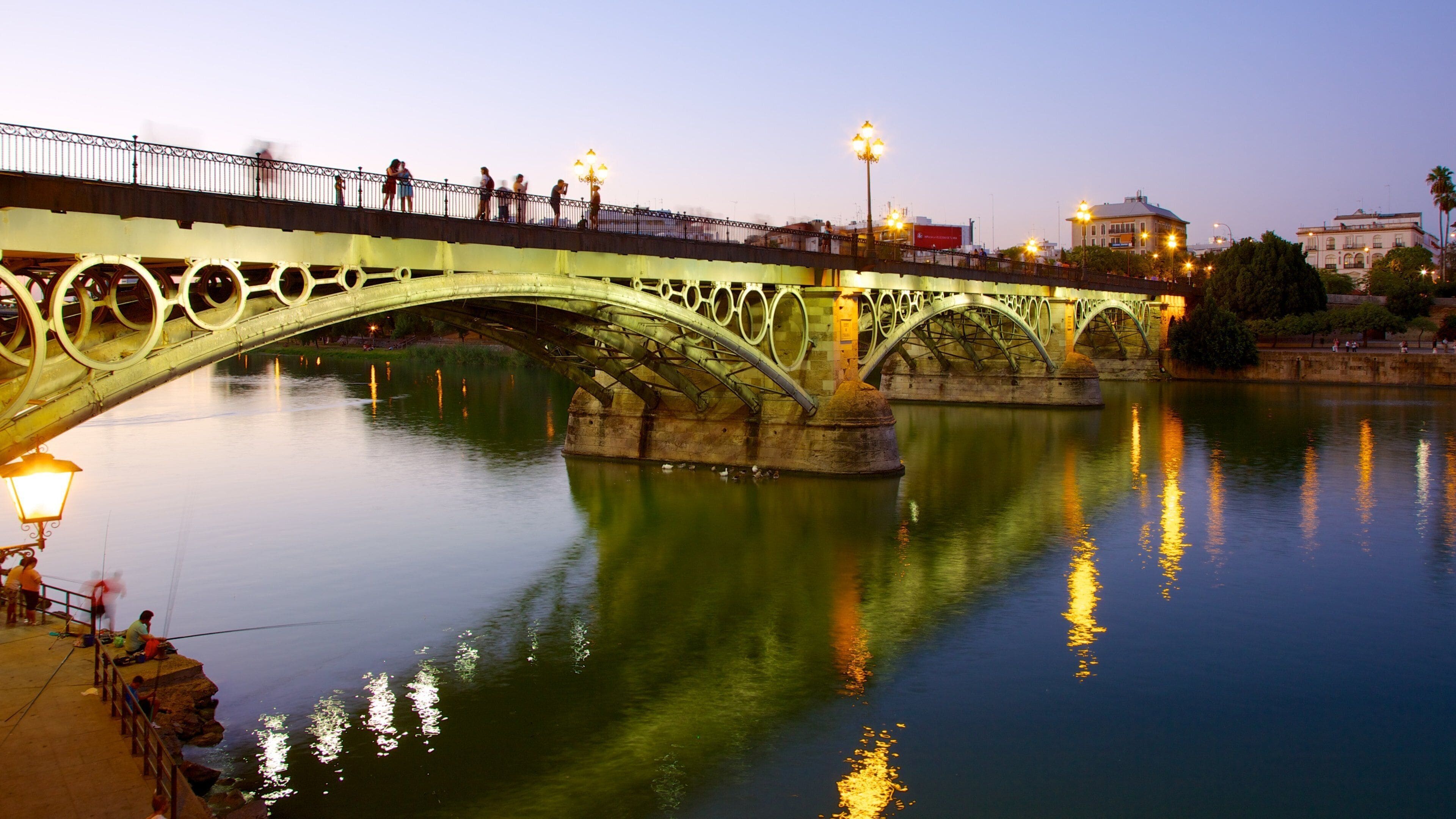Triana Bridge which includes night scenes, a bridge and a river or creek
