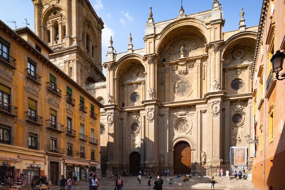 A historic cathedral with ornate architecture, a bustling square, and surrounding buildings.