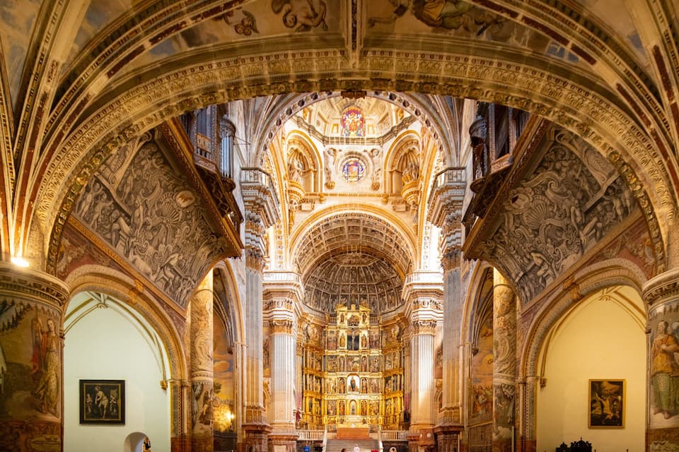 An ornate church interior with detailed frescoes, a central altar, and arched ceilings.