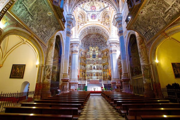 Ein prunkvolles Kircheninnere mit hohen Decken, detaillierten Fresken und Reihen von Kirchenbänken.