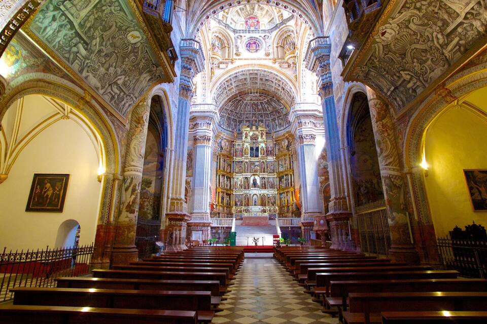 An ornate church interior with high ceilings, detailed frescoes, and rows of pews.