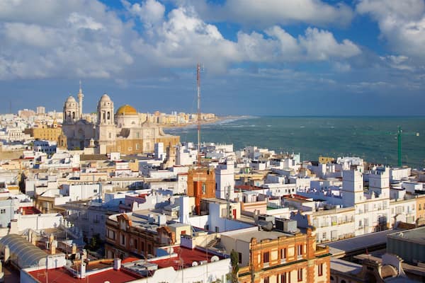 Paisagem costeira com arquitetura histórica, uma igreja imponente e vista clara do mar.