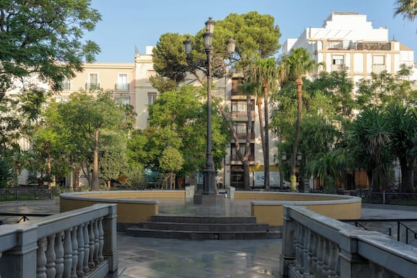 A plaza with a central fountain, surrounded by trees and buildings.