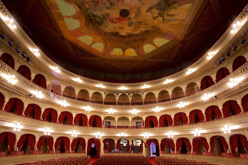 A grand, ornate theater with multiple balconies and red curtains.