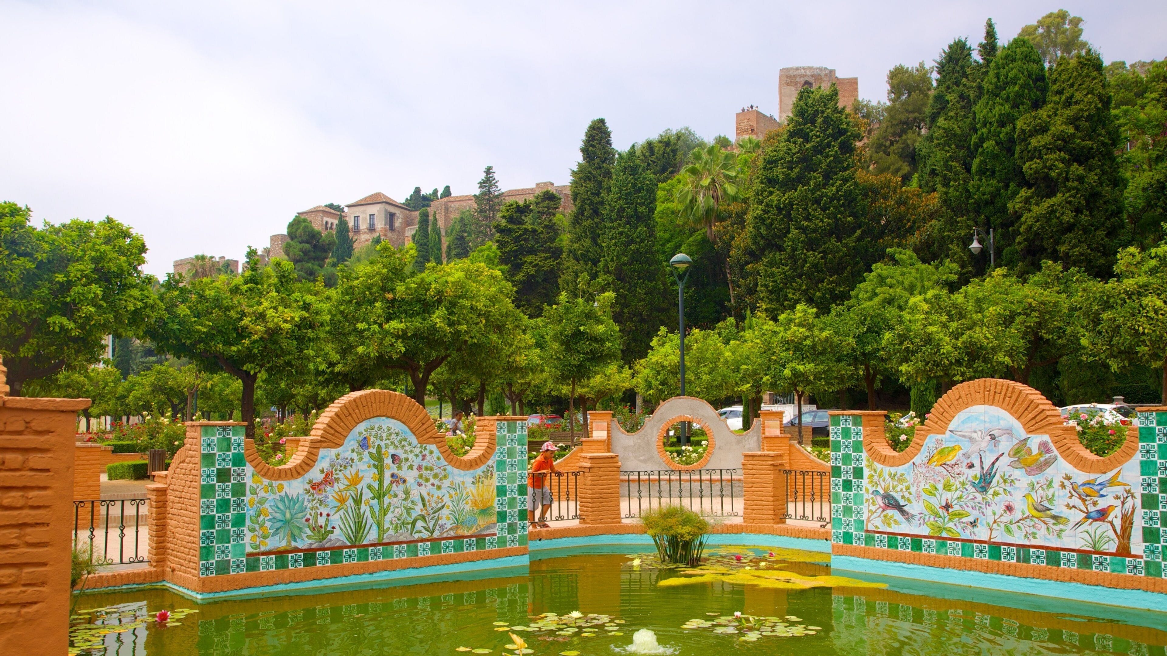 Un parque con un estanque, muros de azulejos y árboles.