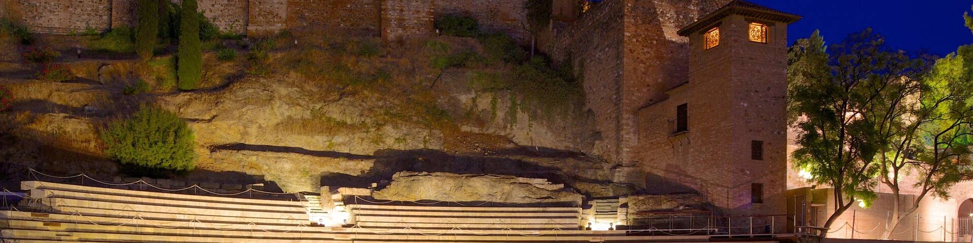 An ancient amphitheater with tiered seating and a stone wall in the background.