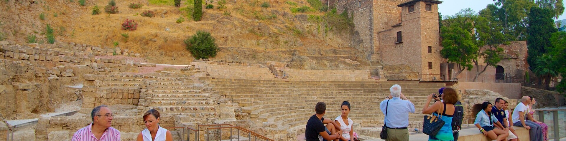 Malaga Amphitheatre which includes heritage architecture and building ruins as well as a large group of people