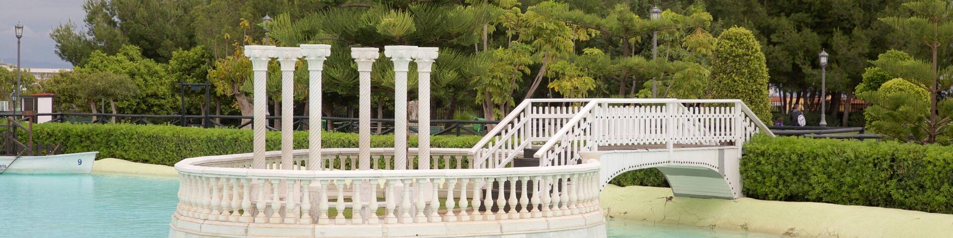 A circular fountain with columns, a bridge, and lush greenery.