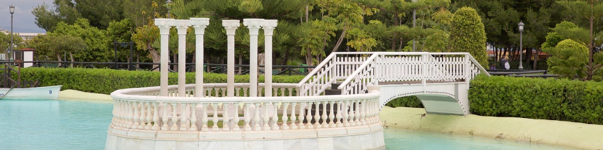 A circular fountain with columns, a bridge, and lush greenery.