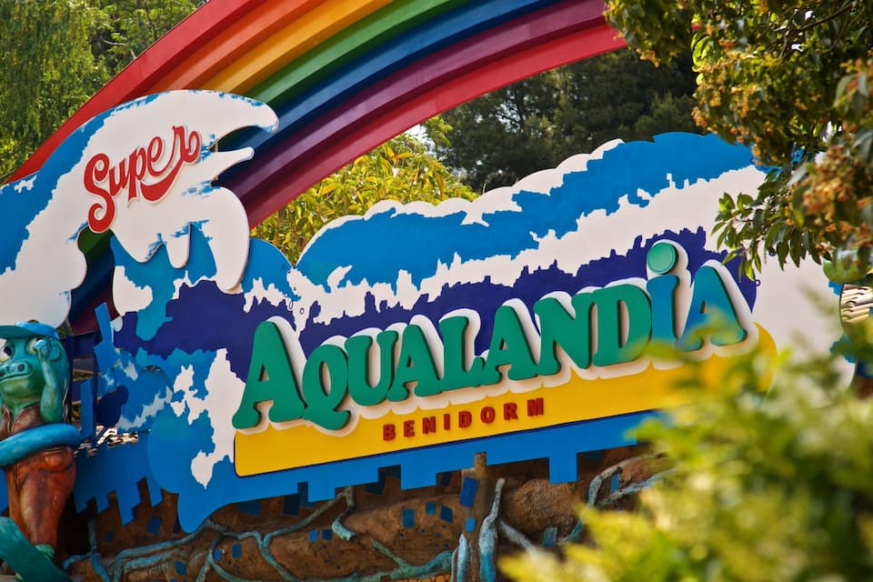 Uma placa colorida com os dizeres 'Super' e 'Aqualandia', rodeada por vegetação.