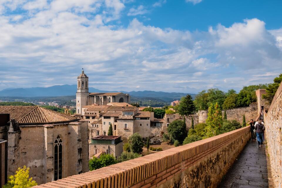 A historic town with a prominent church, a tall bell tower, and a stone bridge.